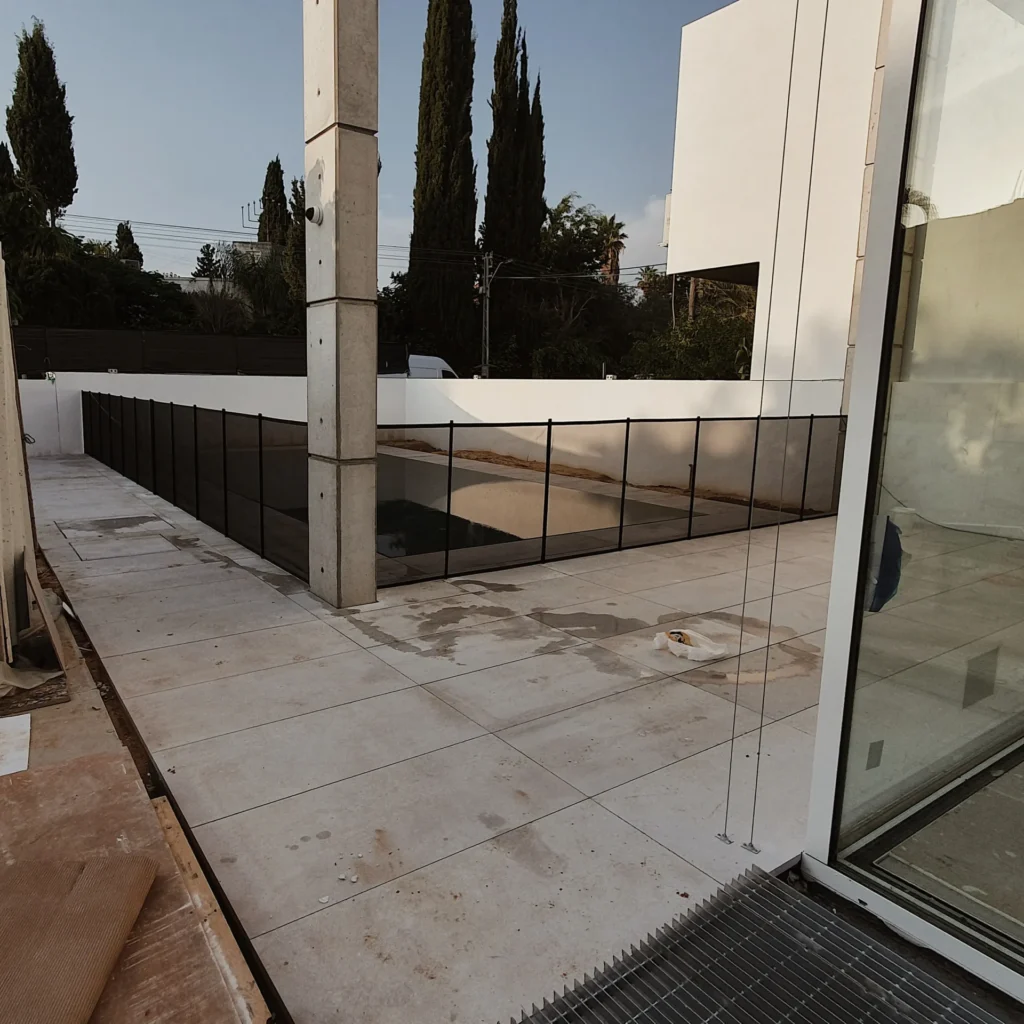 תמונה של גדר רשת שחורה מתוחה בין העמודים ותוחמת את הבריכה